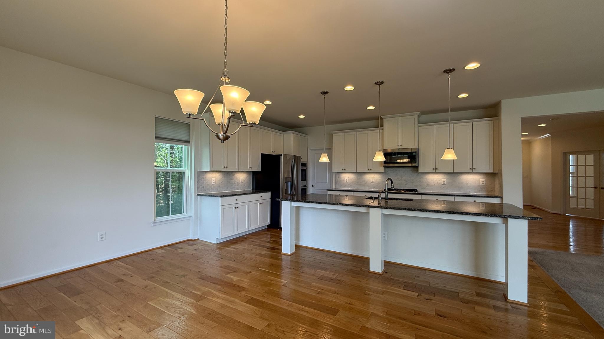12421 Mays Quarter Road Woodbridge, VA 22192 - Photo 3 of 30 a kitchen with stainless steel appliances granite countertop a sink a stove top oven a counter space and wooden floor
