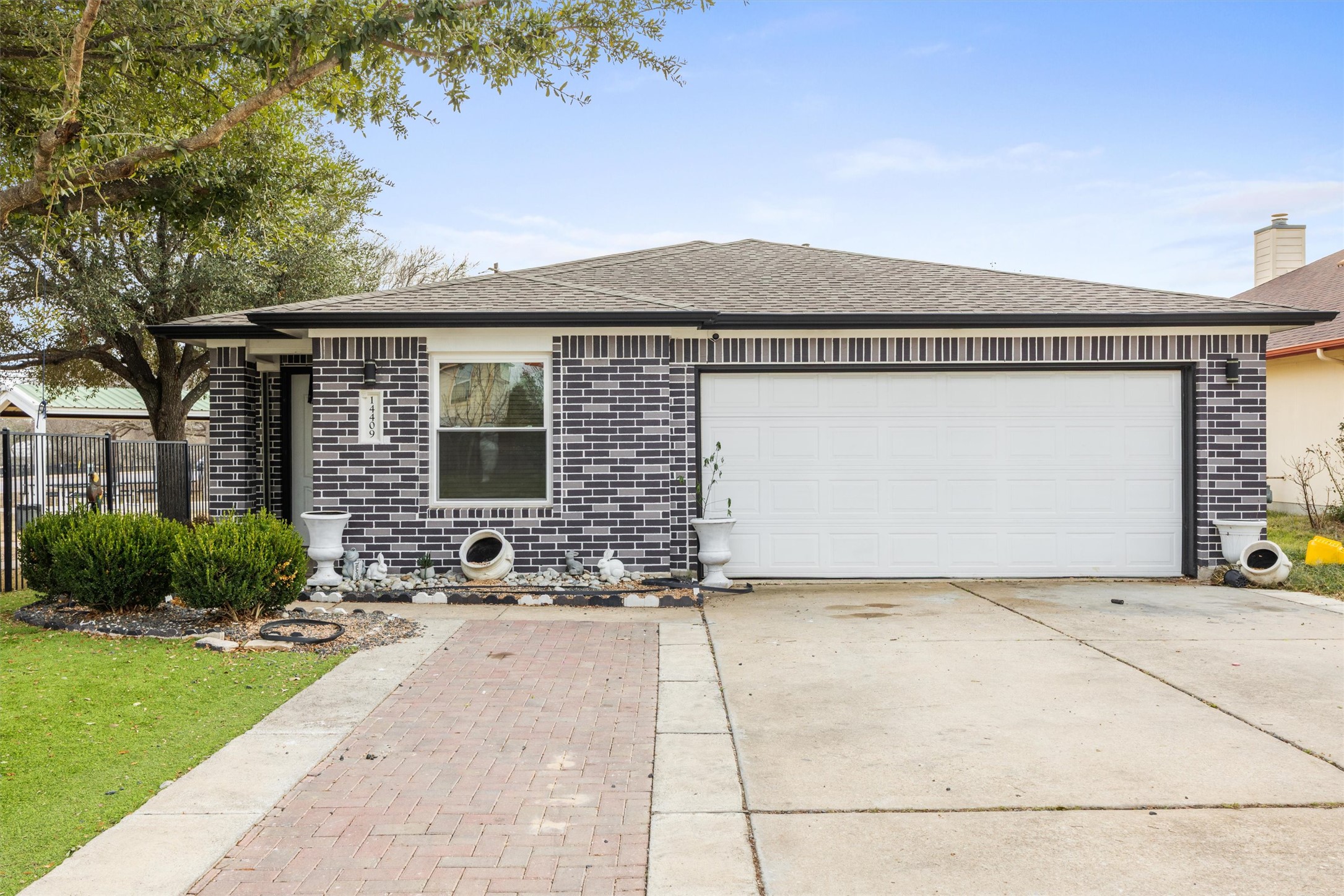 14409 Sandifer Street Austin, TX 78725 - Photo 29 of 31 Single story home with a shingled roof, brick siding, driveway, and a garage