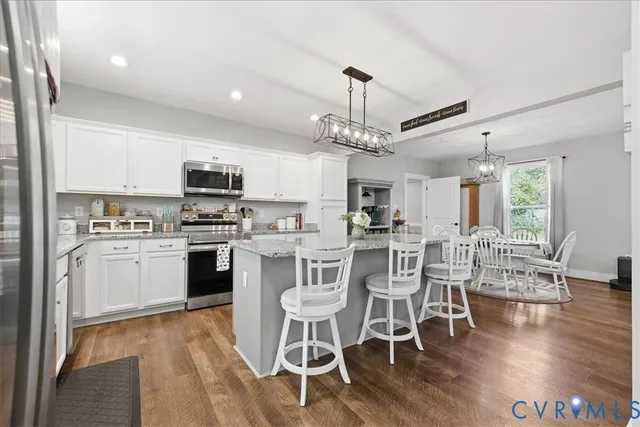 a kitchen with stainless steel appliances a dining table chairs stove and white cabinets