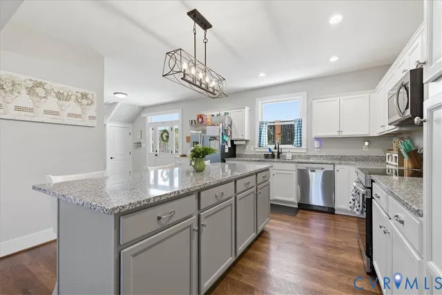 a kitchen with stainless steel appliances granite countertop a sink dishwasher a stove and white cabinets with wooden floor