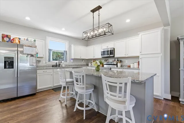 a kitchen with kitchen island white cabinets and stainless steel appliances