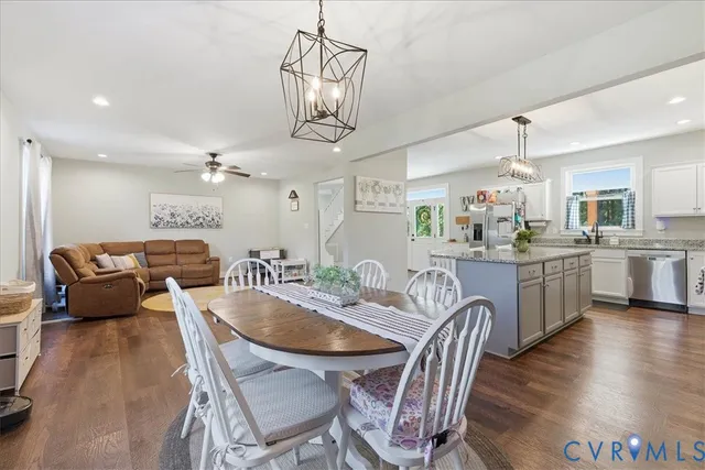 a kitchen with kitchen island granite countertop a dining table chairs sink and wooden floor