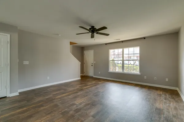 an empty room with wooden floor and windows