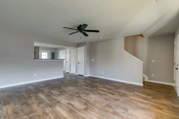 a view of empty room with wooden floor and ceiling fan