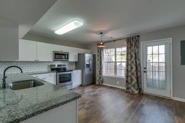a kitchen with stainless steel appliances granite countertop a sink a stove and a refrigerator