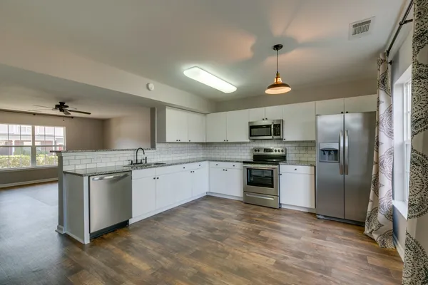 a kitchen with granite countertop stainless steel appliances a refrigerator sink and microwave