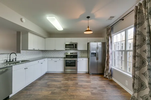 a kitchen with stainless steel appliances granite countertop a refrigerator and a sink