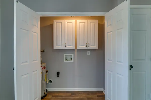a view of an empty room with wooden floor and cabinets