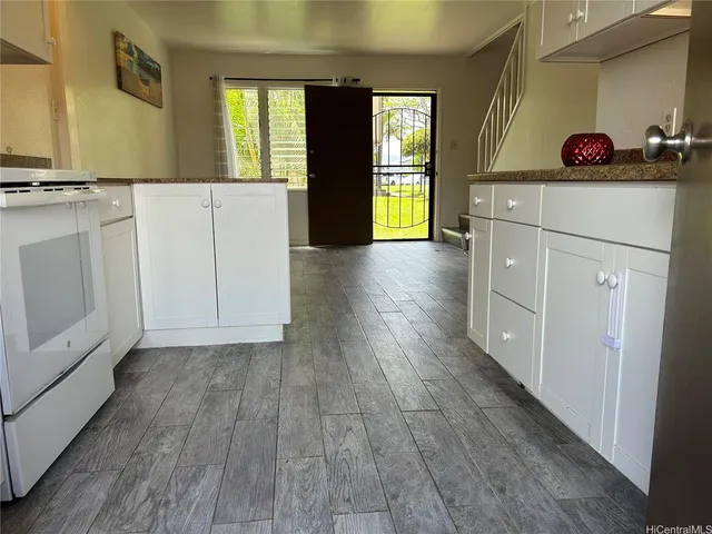 a kitchen with a hard wood floor white cabinets and a dishwasher