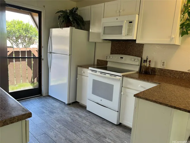 a kitchen with granite countertop white cabinets and white appliances