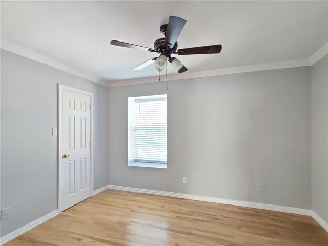 an empty room with wooden floor chandelier fan and windows