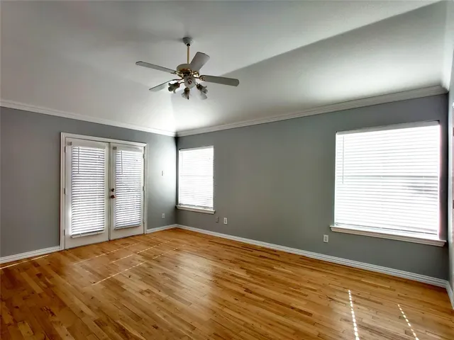 a view of empty room with wooden floor and fan