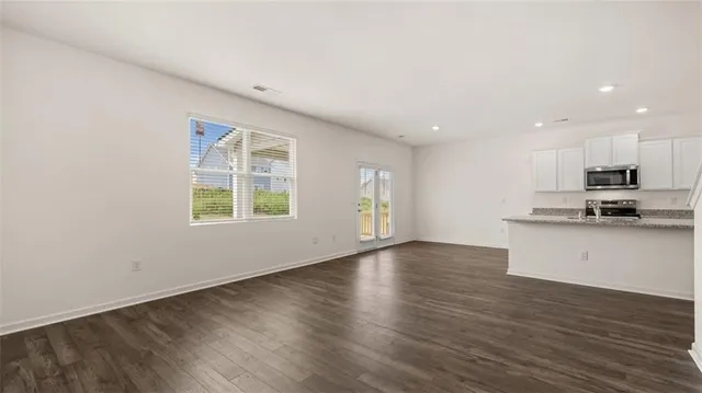 a view of kitchen with kitchen island wooden floors and stainless steel appliances