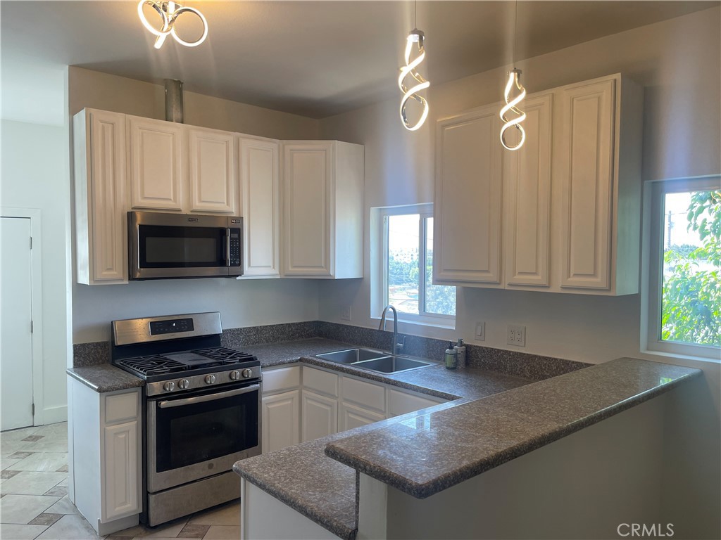 a kitchen with granite countertop a stove a sink and a microwave