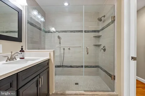 a bathroom with a shower sink vanity and mirror