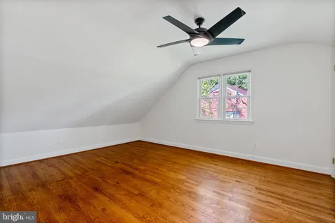 an empty room with wooden floor and ceiling fan