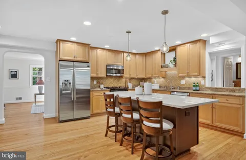 a kitchen with stainless steel appliances a dining table chairs stove and cabinets