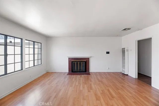 a view of an empty room with wooden floor and a bathroom