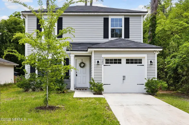 a view of a white house with a small yard and plants