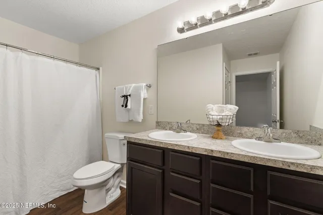 a bathroom with a granite countertop sink toilet and a mirror