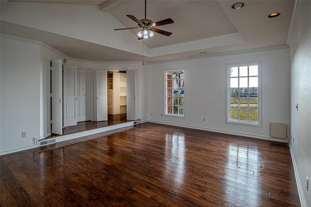 9310 Merritt Road Rowlett, TX 75089 - Photo 21 of 40 an empty room with wooden floor chandelier fan and windows