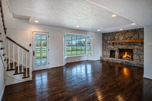 an empty room with wooden floor fireplace and windows