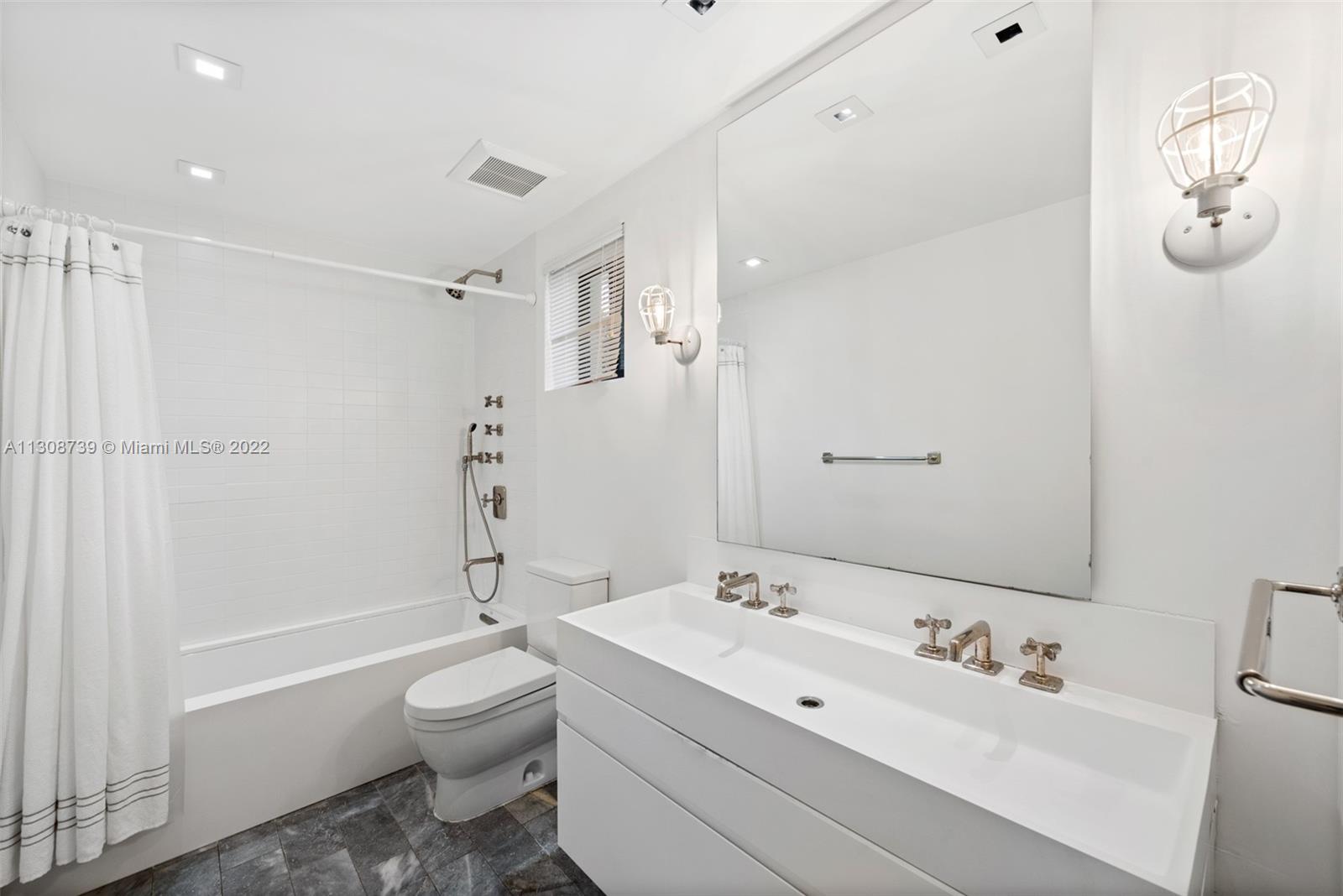 2021 North Bay Road Miami Beach, FL 33140 - Photo 37 of 38 a bathroom with a toilet a sink a mirror a bathtub and shower