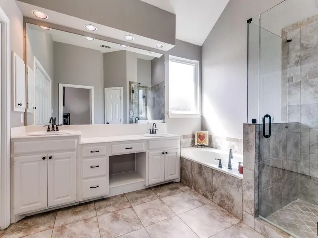 a spacious bathroom with a double vanity sink mirror and bathtub