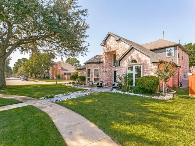 a view of a house with a big yard potted plants and large tree