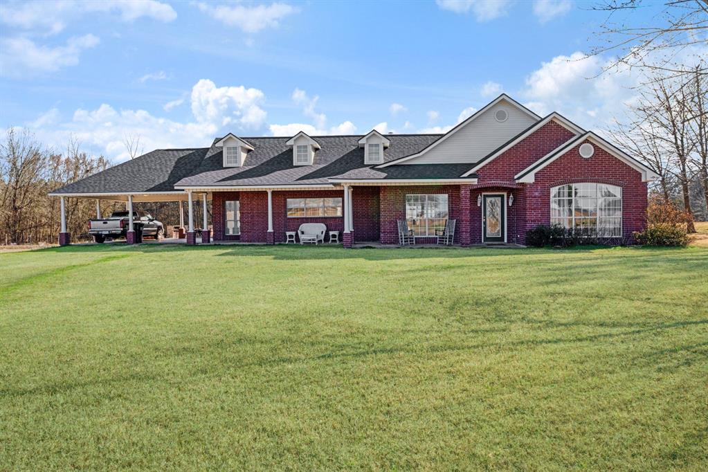 a view of a house with a big yard and large trees
