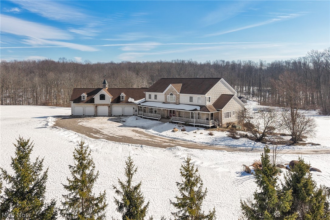 9419 Robinson Road Chardon, OH 44024 - Photo 46 of 46 Snow covered rear of property with a large porch, a wooded view, a garage, and driveway