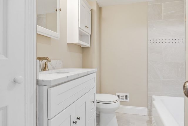 a bathroom with a granite countertop sink a toilet and a shower
