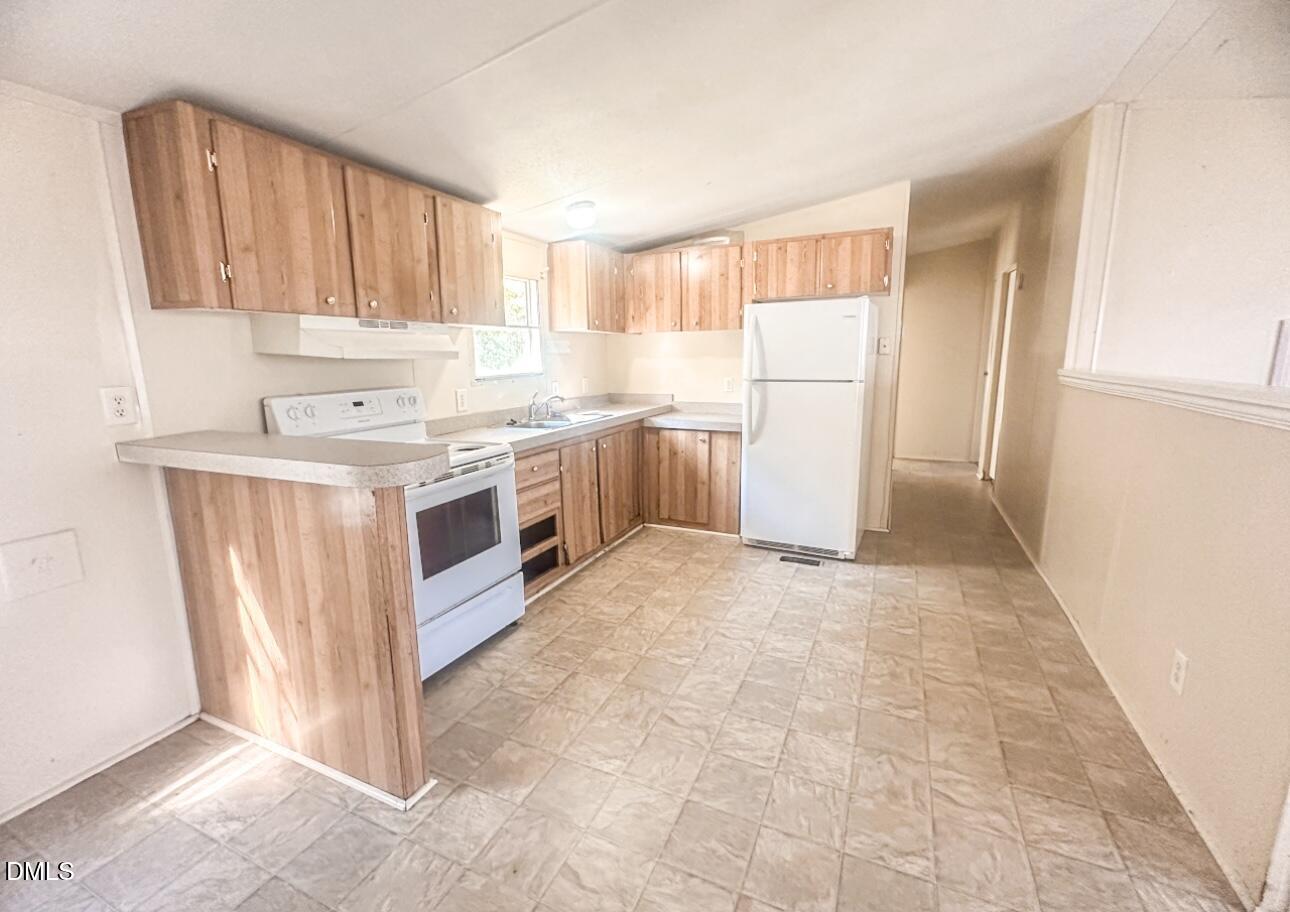 7537 Sam Young Road Oxford, NC 27565 - Photo 14 of 28 a kitchen with a stove a refrigerator and wooden cabinets