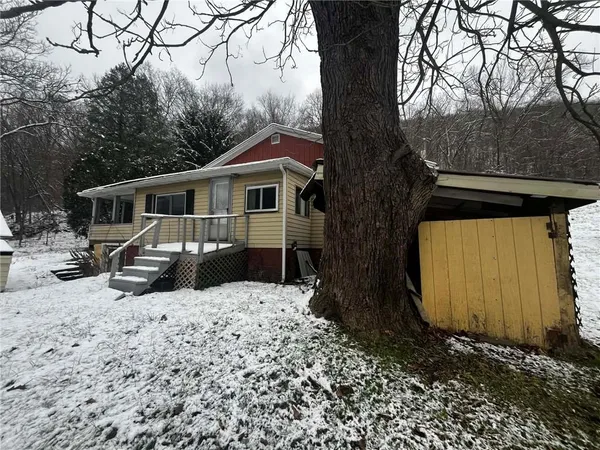 a front view of a house with a yard covered with snow