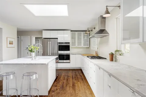 a large kitchen with stainless steel appliances granite countertop a sink a stove and a wooden floors