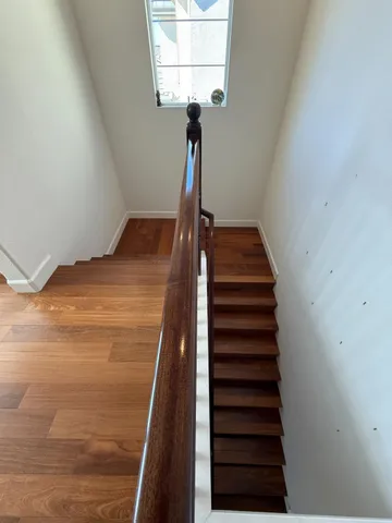 a view of a hallway with wooden floor and staircase