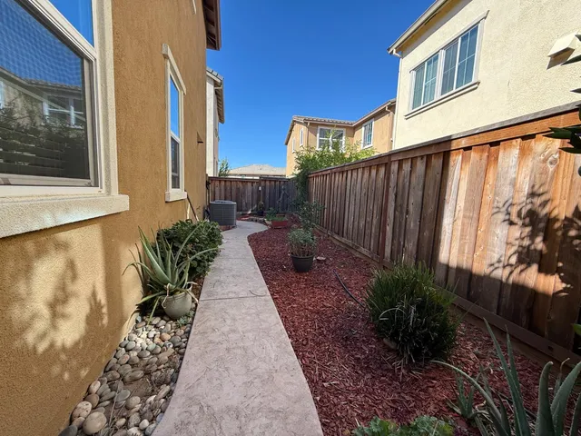 a view of a patio with table and chairs potted plants and floor to ceiling window and wooden fence