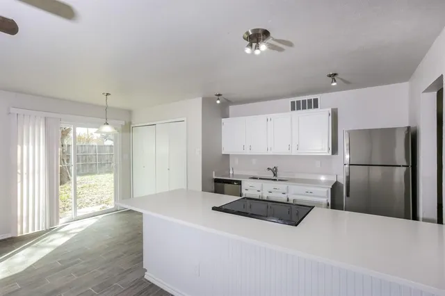 a kitchen with stainless steel appliances a refrigerator a sink a stove a dining table and chairs