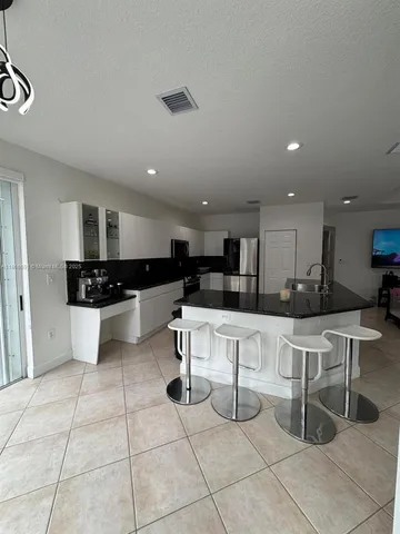 a kitchen with stainless steel appliances kitchen island granite countertop a sink and white cabinets