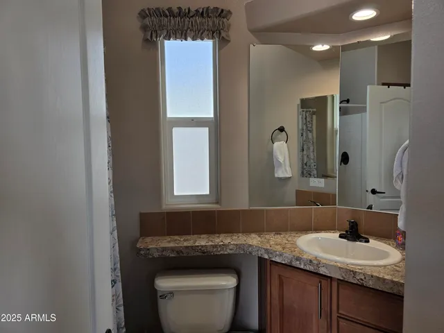 a bathroom with a granite countertop sink toilet and mirror