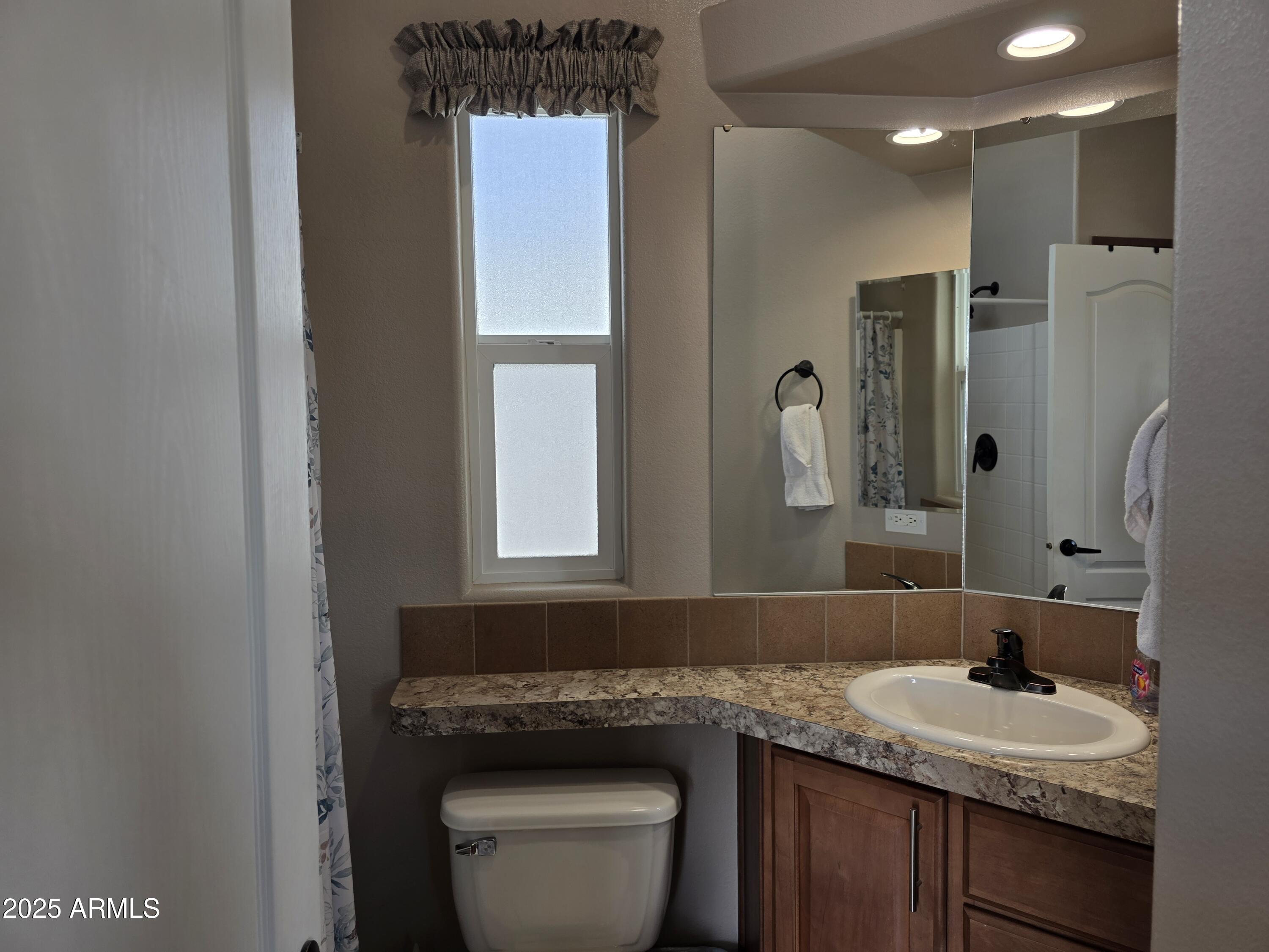 1457 South Zuni Avenue, Unit 457 Apache Junction, AZ 85119 - Photo 11 of 12 a bathroom with a granite countertop sink toilet and mirror