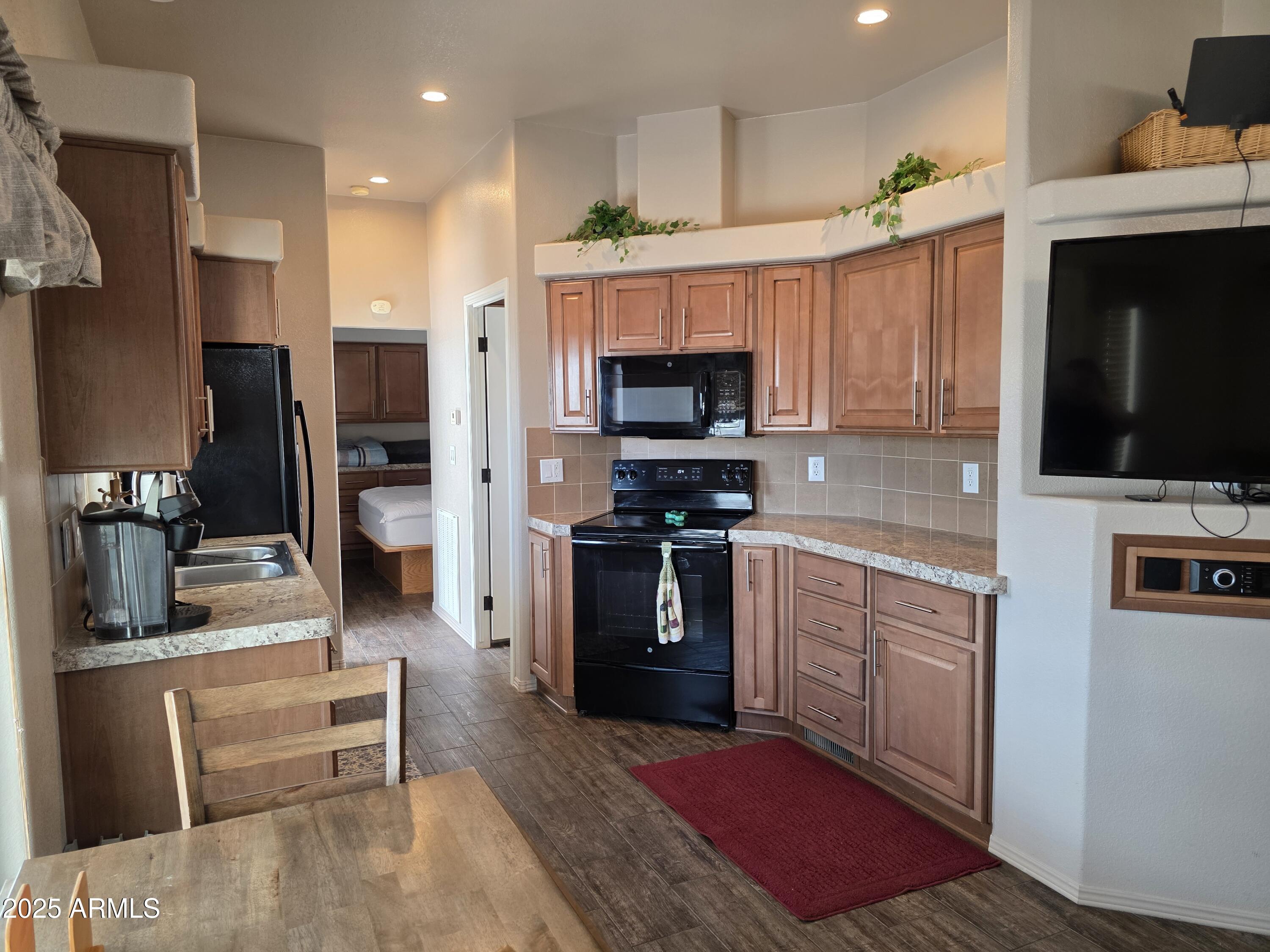 1457 South Zuni Avenue, Unit 457 Apache Junction, AZ 85119 - Photo 8 of 12 a kitchen with stainless steel appliances kitchen island granite countertop a stove top oven a sink and a refrigerator