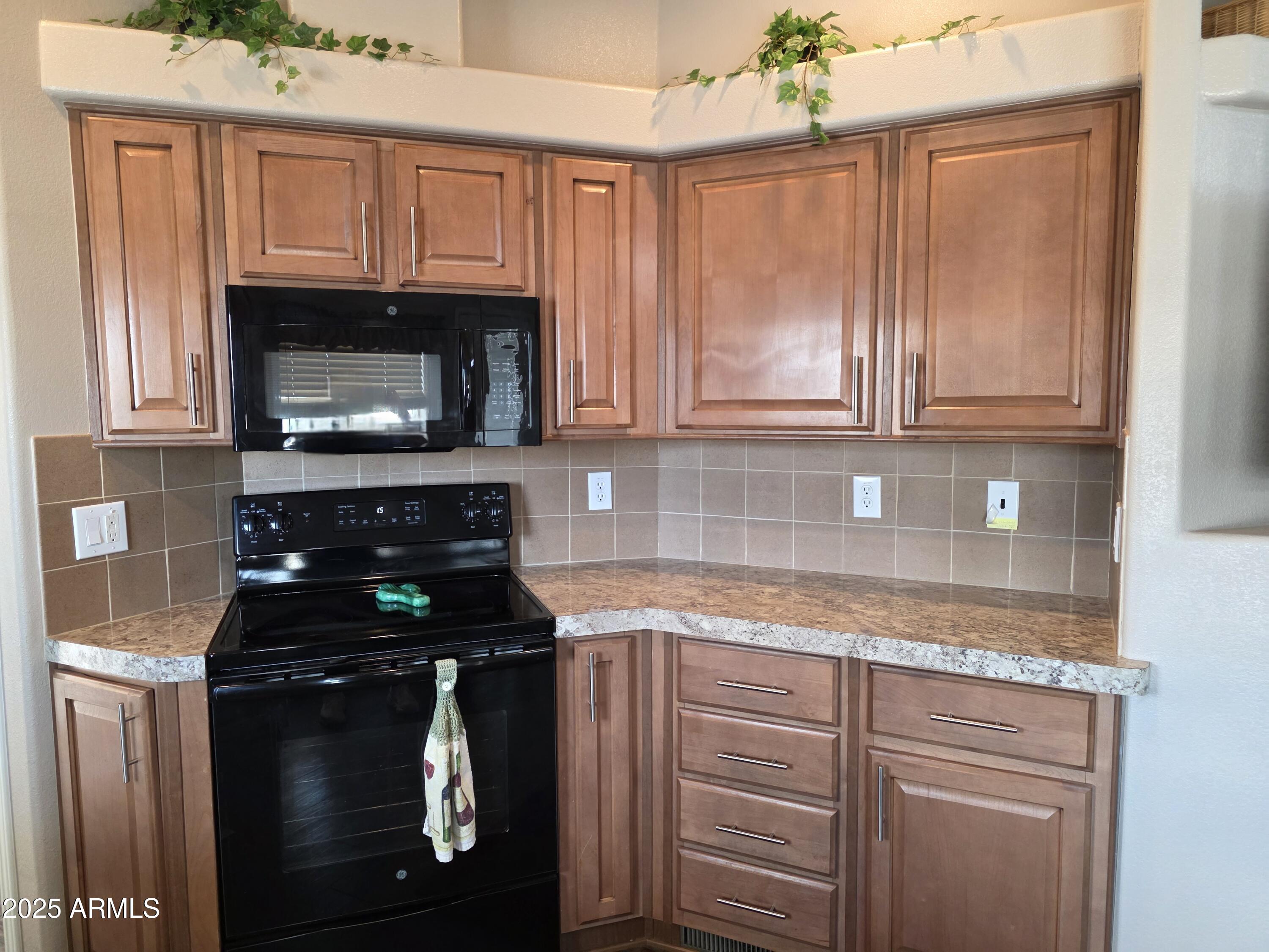 1457 South Zuni Avenue, Unit 457 Apache Junction, AZ 85119 - Photo 9 of 12 a kitchen with granite countertop wood cabinets and a stove top oven