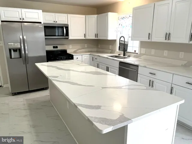 a kitchen with stainless steel appliances granite countertop a sink a stove and a refrigerator