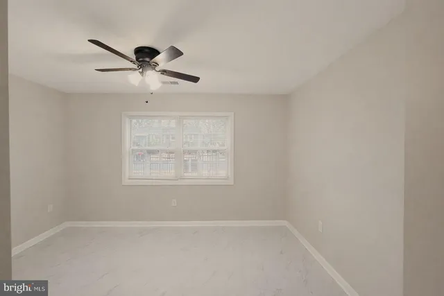 an empty room with a window and a fan