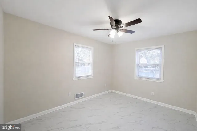 a view of an empty room with a ceiling fan and a window