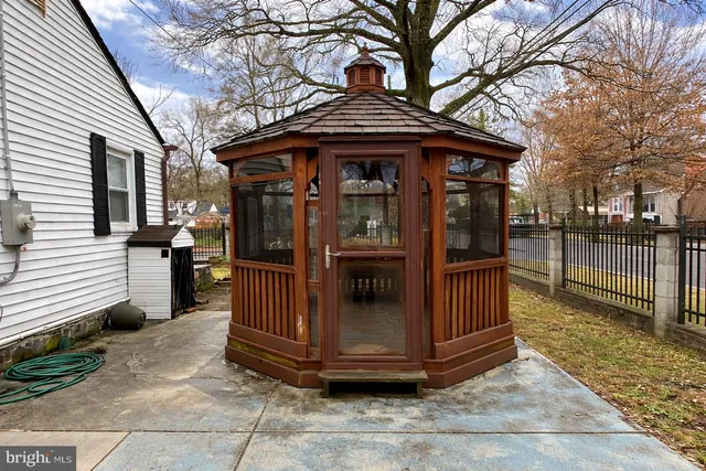 a view of a house with a wooden fence and a large tree