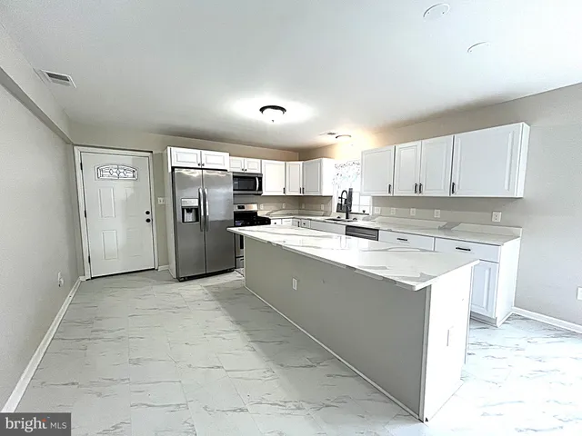 a large kitchen with stainless steel appliances granite countertop a stove a sink a refrigerator and white cabinets