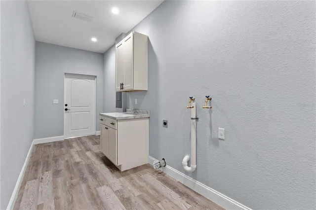 a view of a kitchen with white cabinets and wooden floor