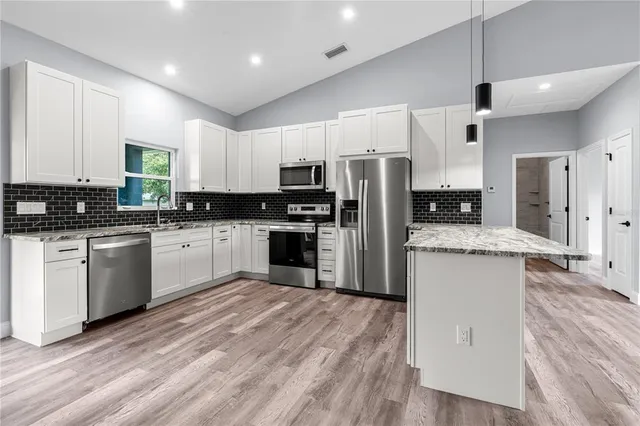 a kitchen with granite countertop a sink cabinets and stainless steel appliances